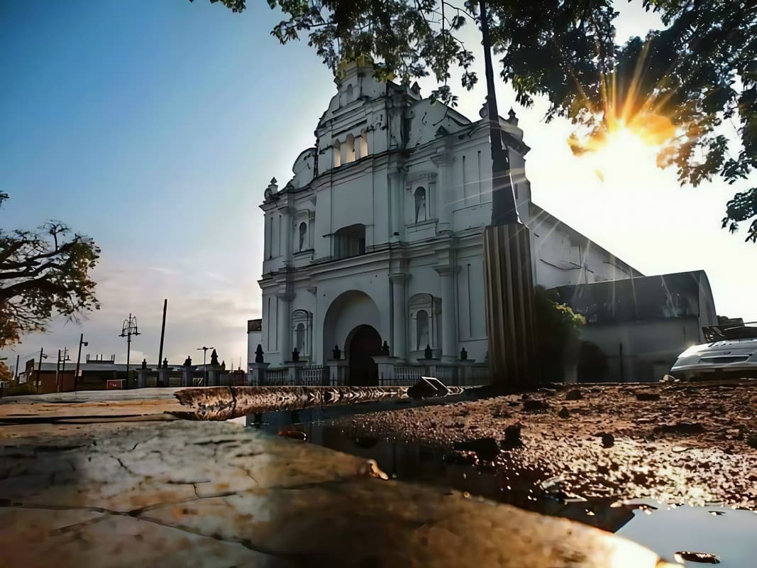 Iglesia de San Luis Jilotepeque al amanecer, con el sol entre los árboles